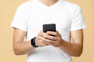Sosyal ağlar, bloglar ve mobil uygulamalar. Gözlüklü, akıllı saati olan, beyaz tişörtlü, gülümseyen genç blogger öğrenci. Telefonu tut ve internetten izole bir şekilde internette sörf yap.