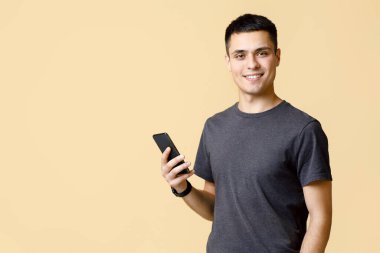 Blog takipçilerine mesaj yazan modern öğrenci blogcusu. Dost canlısı, kendine güveni tam genç bir adam. Akıllı saat. Telefonu tut ve kameraya bak.