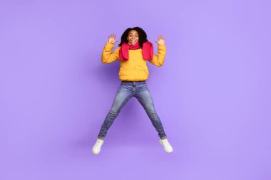 Hoş geldiniz. Neşeli Afrikalı Afrikalı Amerikalı Kadın Orta-havada el sallıyor ve kameraya gülümsüyor. Mavi stüdyo arka planında kalın bir ceket giyiyor. Kış Reklam Bayrağı. Tam Uzunluk Çekimi