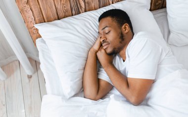 Afro-Amerikan Adam, gözleri kapalı, evinde, yatak odasında rahat bir şekilde yatarken huzur içinde uyuyor. Eğlence, Sağlıklı Erkek Uyku, Uyku Vakti Konsepti. Metin için Boşluk