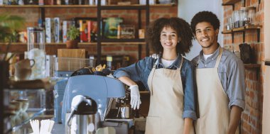 Tecritten sonra modern kafede müşterilerle buluşup onları beklemek. Binlerce yıllık gülümseyen Afro-Amerikan erkek ve kadın önlüklü ve eldivenli kafeteryada sabahları espresso makinesi ve ekipmanla