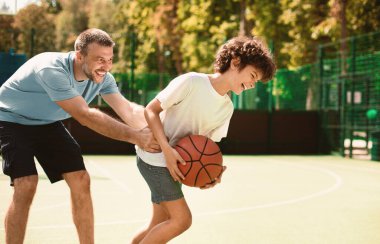 Bağlanma kavramı. Baba ve oğlunun birlikte basketbol oynamalarının portresi. Adam topu yakalamaya çalışıyor.