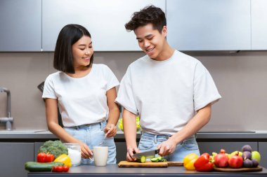 Sağlıklı yemek tarifi. Çinli koca ve eş, modern mutfakta sebze pişiriyor, taze sebzeleri kesiyor, evde birlikte yemek hazırlıyorlar. Gıda Hazırlama ve Aile Beslenme Konsepti