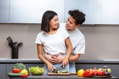 Neşeli Çinli çift evde mutfaktayken birlikte yemek hazırlıyor. Hafta sonu taze sebze salatası yapan harika bir aile. Beslenme, Sağlıklı Tarifler ve Gıda Hazırlama Konsepti