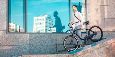 Şehirde çalışmak için kısa bir yol. Bisikletle merdivenlerden inen genç adam, dışarıda, fotokopi odasında.