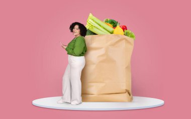 Taze yiyeceklerle dolu büyük bir kesekağıdının yanında bir müşteri görülüyor. Birey telefonuyla meşgul görünüyor, uzaktan alışverişe geçişi gösteriyor..