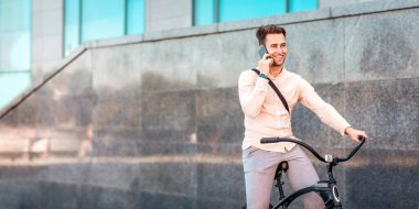 Yolculuk sırasında, açık havada, akıllı telefondan iletişim. Sokakta bisikleti olan genç ve zarif bir iş adamı.