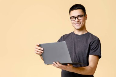 Serbest çalışmak ve evde internetten kendini izole etmek. Gözlüklü, dizüstü bilgisayarı olan, internette sörf yapan, aydınlık arka planda izole edilmiş, boş bir alanda yaşayan yakışıklı bir adam.
