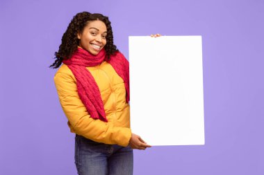 Neşeli Afro-Amerikalı Kadın Mavi Stüdyo Arkaplanı Üzerinde Boş Poster İlan Veriyor. Sıcak Giysiler Giyen Kadın İlan Kurulu Metni. Model