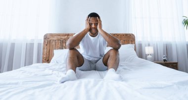 Uykusuzluk ve uyuyakalma. Yatakta uyuyakalmış Afrikalı Amerikalı Stresli Adam, Dokunaklı Kafası Evdeki Yatak Odasındaki Şokta Kameraya Bakıyor. Stresli Hayat, Uykusuzluk Konsepti. Panorama