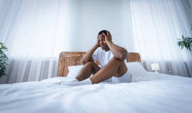 Anksiyete ve Uykusuzluk. Stresli siyah milenyum adamı yatakta oturuyor, kafaya dokunuyor evdeki sorunları düşünüyor. Panorama, Düşük Açı
