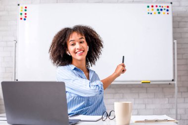 Modern eğitim uzaktan. Neşeli genç Afrikalı Amerikalı kadın tahtaya işaret ediyor ve İngilizce kurallarını internetten açıklıyor.