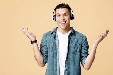 Rahatla, favori müzik, boş zamanlarında eğlence ve zevk. Modern kulaklıklarla gülümseyen heyecanlı öğrenci ellerini yanlara açıyor, kumlu arka planda izole edilmiş, boş alan.
