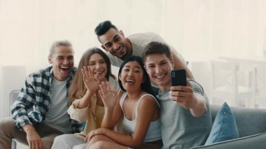 Farklı bin yıllardan bir grup mutlu bir şekilde modern, parlak bir oturma odasında toplanmış kahkahalarımızı paylaşıp selfie çekiyorlar. Canlı etkileşimleri neşe dolu bir arkadaşlığı yansıtıyor..