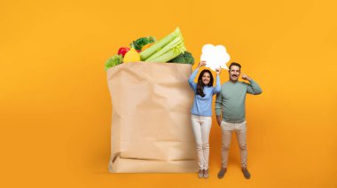 İki birey taze sebze ve meyvelerle dolu büyük bir kesekağıdının yanında duruyor, gülümsüyor ve konuşma baloncukları tutuyor. Modern zamanlardaki market alışverişinin zevkini yansıtıyor..
