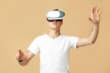 Modern VR gözlüklü adam sanal gerçekliği keşfediyor. Beyaz tişörtlü ve gözlüklü ciddi bir genç adam ellerini kumdan ya da aydınlıktan izole edilmiş bir şekilde aletleri kontrol ediyor.