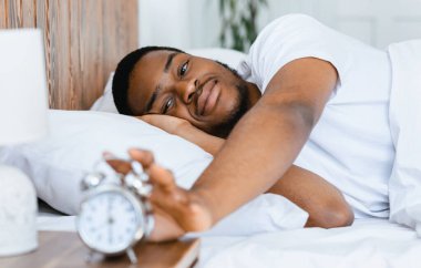 İyi sabahlar. İyi uykular siyah adam alarmı kapatıyor uyandığında evdeki modern yatak odasında yatıyordu. Erken Uyanış, Kalkma zamanı. Seçici Odaklanma