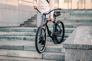 Şehir ve çevre taşımacılığında işe giderken, sabahları sağlıklı bir yaşam sürüyor. Şık giyinmiş hippi bir adam modern bisikleti şehir merdivenlerinde, açık havada, dikey