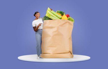 Gülümseyen bir müşteri içi taze ürün ve bakkaliye dolu büyük bir kesekağıdını işaret eder. Bu an, alışveriş ve teslimatın özünü çağdaş bir ortamda yakalıyor..