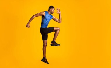 Egzersiz yapıyorum. Yüksek dizli, bacak kaldıran ve el sallayan kollu kaslı afro adamın tam boy portresi.