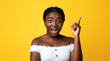 Fikir kavramı. Heyecanlı Afrikalı Amerikalı Kadın Parmağını Kalkmış, Çözüm Bulmak ya da İlham Vermek, Eureka 'yı Övüyor, Duygusal Siyah Kadın Sarı Stüdyo Arkaplanında Pozunu Veriyor, Boşluğu Kopyala