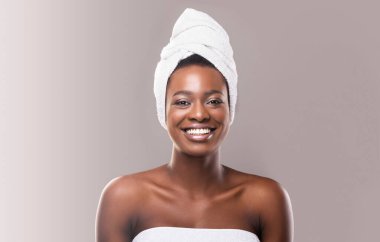 Güzel genç afrikalı kadın sauna için hazırlanıyor beyaz banyo havlusu sarılmış, gri stüdyo arka plan
