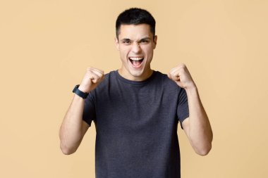 Başarı, zafer ve iş ya da işte şans. Akıllı saatli neşeli genç adam kameraya bakar ve kazanma ve başarı duygularını ifade eder, arka planda izole edilmiş, boş alan, stüdyo çekimi