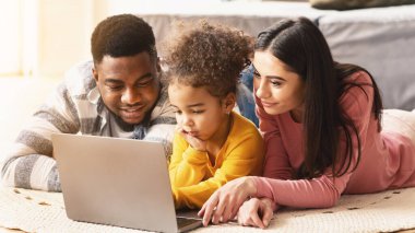 Uluslararası aileler çocuklara yerde yatan bilgisayarı kullanmayı öğretiyor.