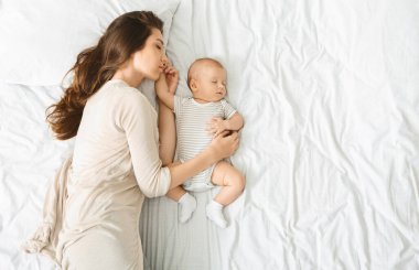 Bebeklerle birlikte uyumak. Milenyum annesi, tatlı bebeğini uyurken kucaklıyor.