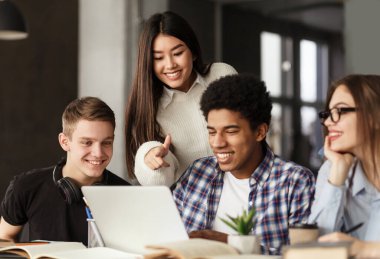 Kütüphanede dizüstü bilgisayar kullanan üniversite öğrencileri, okul ödevi için birlikte eğitim