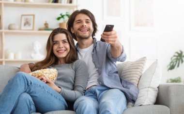 Evde televizyon izliyordum. Sevgili çift kanepede dinleniyor ve patlamış mısır yiyor.