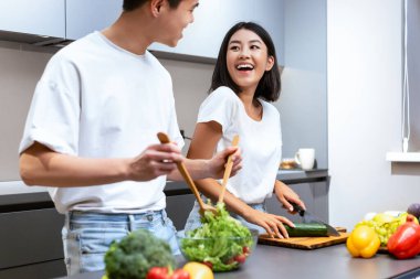 Mutlu Çinli eş ve koca mutfakta yemek pişiriyor, hafta sonları akşam yemeği için taze sebze salatası hazırlıyor. Aile gıdası ve sağlıklı yemek tarifleri. Kırpılmış, Seçici Odaklanma