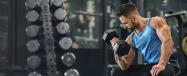 Vücut geliştirici kollarını spor salonunda dambılla pompalıyor, boş alan, web pankartı