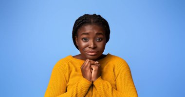 Please, Buy. Cute black woman pleading and asking for something with clasped hands, young african lady with begging face expression posing over purple studio background, looking at camera, copy space