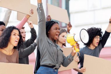 Boş pankartlı öfkeli çok ırklı öğrenciler grev ya da sokakta gösteri yapıyorlar. Motive olmuş Afro-Amerikalı kadın hoparlörle dışarıda kalabalığın önünde sloganlar atıyor.