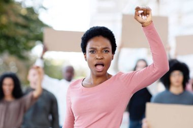 Dünya barışı için savaşan, sokaklarda yürüyen, boş pankartlı uluslararası bir grup öğrenci. Afrika kökenli Amerikalı genç bir kadın. Çok ırklı protestocuların lideri. Yumruklarını kaldırıyor.