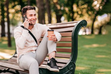İş adamı ya da yönetici, park molasında müşteriyle konuşur. Neşeli genç adam yönetici bankta oturur, kahvesini alır ve şehir merkezinde, bisiklet yakınında, açık havada, serbest alanda akıllı telefonda konuşur.