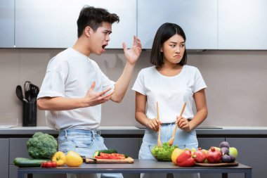 Saldırgan Asyalı koca, evde mutfakta yemek hazırlarken karısına bağırıyor ve onu gücendiriyor. Mutsuz Evlilik Hayatı, İlişki Krizi, Sorunlar ve Çatışmalar