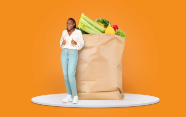 Neşeli bir müşteri, içi taze sebze ve meyve dolu büyük bir kesekağıdıyla poz veriyor. Bu resim, izolasyon sırasında modern market alışverişini sembolize eder..