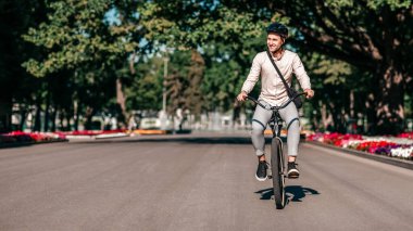 Genç bir adam, canlı çiçeklerle çevrili, ağaçlarla kaplı sessiz bir cadde boyunca bisikletini sürüyor. Rahat bir yaşam tarzı sergiliyor, güneşli bir günde açık havayı kucaklıyor, uzayı kopyalıyor.
