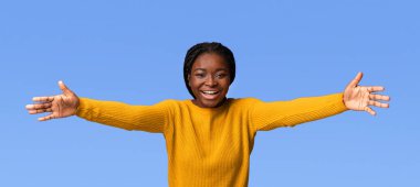 Dost canlısı Afrikalı Amerikalı kadın kameraya doğru elini çekiyor, birini selamlıyor, pozitif siyah kadın kucaklaşmak için kollarını açıyor, mor stüdyo arka planının başında duruyor, mekanı kopyalıyor.