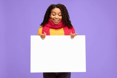 Kış Teklifi. Siyah Milenyum Kadını Boş Poster Tutuyor Mavi Stüdyo Arkaplanının Üzerinde Kalın Kıyafetler Giyiyor. Metin Reklamı Konsepti için Bayan Boş Tahta Gösteriyor. Model