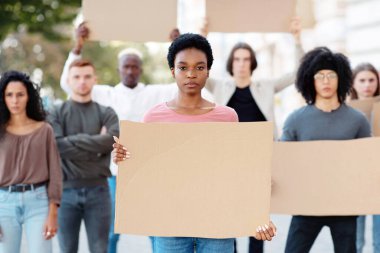 Sokaktaki bir grup göstericiye önderlik eden Afrikalı Amerikalı genç bir kadın. İnsan ya da hayvan haklarını ve ırkçılığı protesto eden boş pankartlı uluslararası bir grup insan