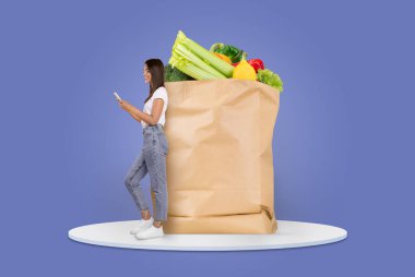 Bir müşteri, mobil bir cihazı kontrol ederken içi taze ürünlerle dolu büyük bir kesekağıdının yanında duruyor. Bu, market alışverişinin özünü modern ve izole bir ortamda yakalar..