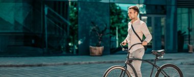 Genç bir adam güneşli bir şehir sokağında bisikletini gelişigüzel sürüyor, bin yıllık bir yaşam tarzını somutlaştırıyor. Şık kıyafetler giyiyor ve etrafındaki canlı kentsel çevreden hoşlanıyor.