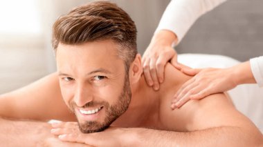 Hafta sonu kaplıcaya giden mutlu orta yaşlı adam, kapanış. Sırt masajı yaptırırken kameraya gülümseyen yakışıklı sakallı adam. Kadın terapist spa salonunda neşeli erkeğin omuzlarını ovuyor.