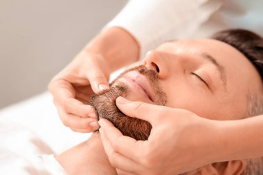 Lüks kaplıcalarda orta yaşlı bir adamın yüz masajı yaptırması. Kaplıca terapisti yakışıklı bir adam için rahatlatıcı bir masaj yapıyor sakallı çenesini ovuyor, fotokopi çekiyor. Erkek kozmetoloji kavramı