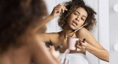 Kahve içme ve banyo ayna önünde aynı anda telefonla konuşurken Afro-Amerikan Kız Makyaj, acele et. Özür dilerim, geç bugün kavramı.
