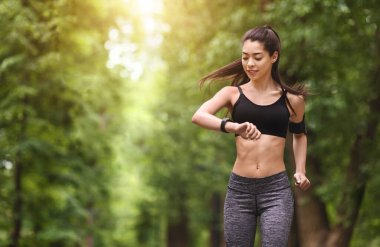 Trail Running Concept. Genç adam koşuyor ve akıllı kol saatine bakıyor, fotokopi alanı, açık hava.