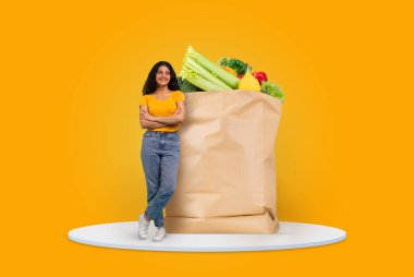Bir müşteri kendine güvenen bir şekilde renkli sebze ve meyvelerle dolu büyük bir kesekağıdının yanında duruyor. Parlak arka plan, bugünün marketlerinde alışveriş yapmanın keyfini vurguluyor..